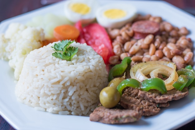 Brazilian food dish Beans, rice, meat, eggs, salad.