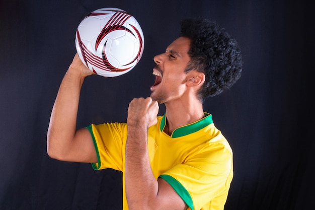 Бразильский футбольный черный игрок держит мяч и празднует
