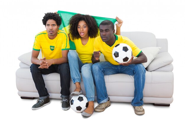 Brazilian football fans in yellow sitting on the sofa