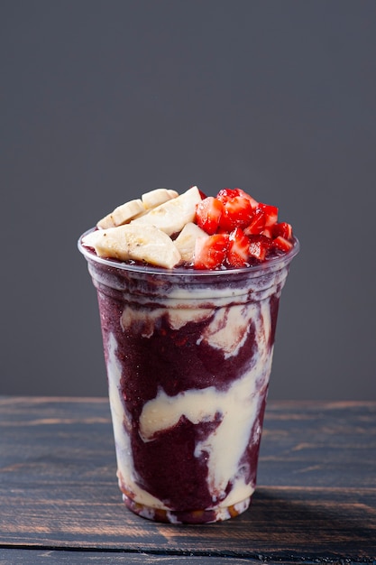 Brazilian frozen açaí­ in a plastic cup with condensed milk, banana and strawberry. Fruit from the Amazon.  