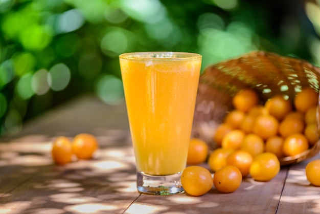 Brazilian fruit caja. Glass of juice on wooden table.