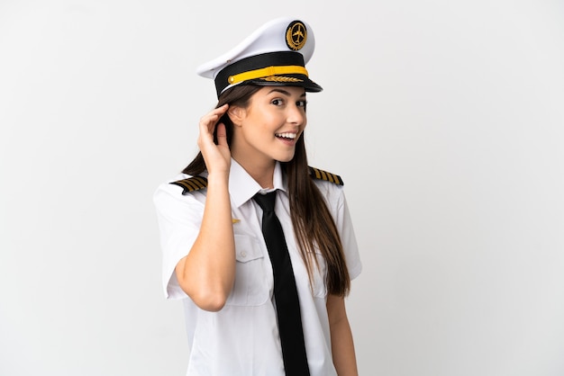 耳に手を置いて何かを聞いている孤立した白い背景の上のブラジルの女の子の飛行機のパイロット