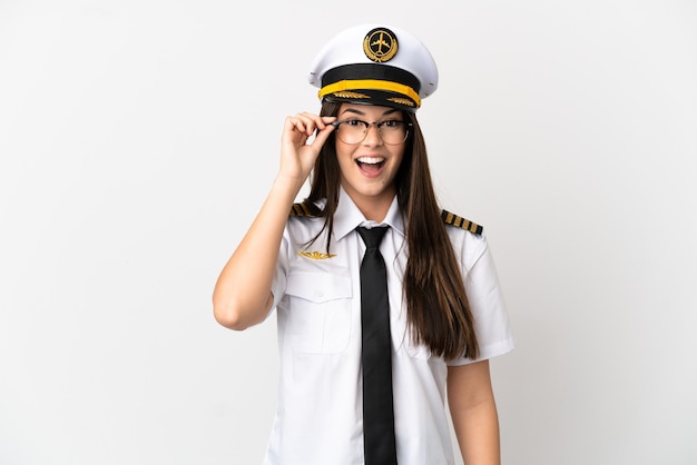 Бразильская девушка пилот самолета на изолированном белом фоне в очках и удивлен