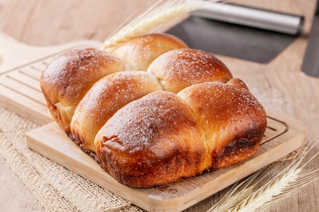 Brazilian Homemade bread on top of a wooden countertop, with flour spread over the counter and wheat.  