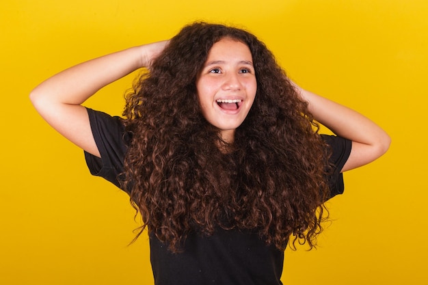 Фото Бразильская латиноамериканская девушка для афро волос желтый фон руки на голове символ волос вьющиеся волосы кудри причесанные волосы красивые волосы продукты для волос