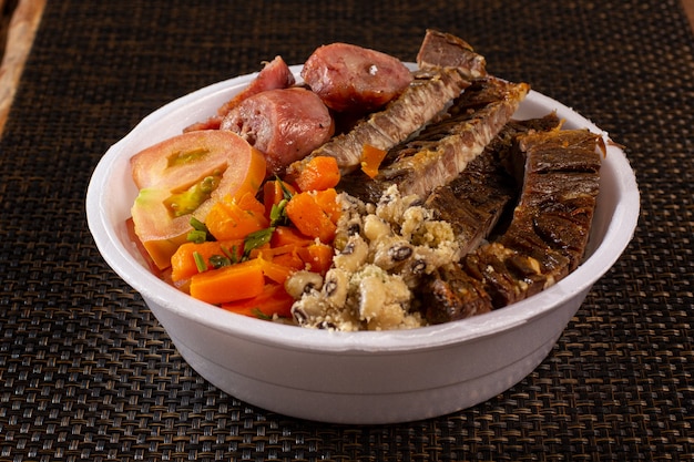 Photo brazilian lunchbox with barbecue meat sausage salad rice beans and farofa