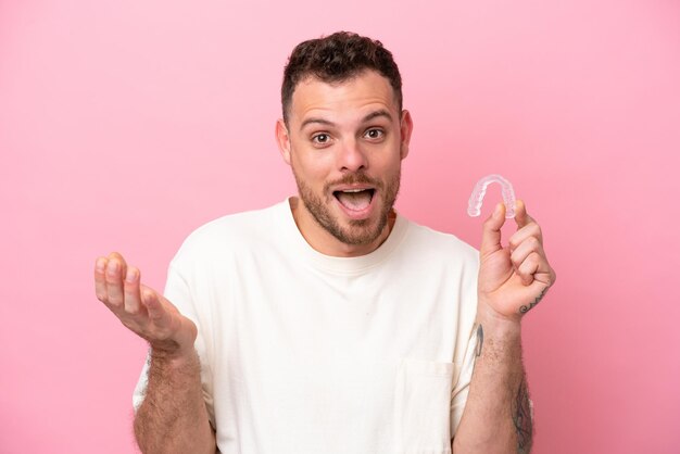 Brazilian man holding invisible braces with shocked facial expression