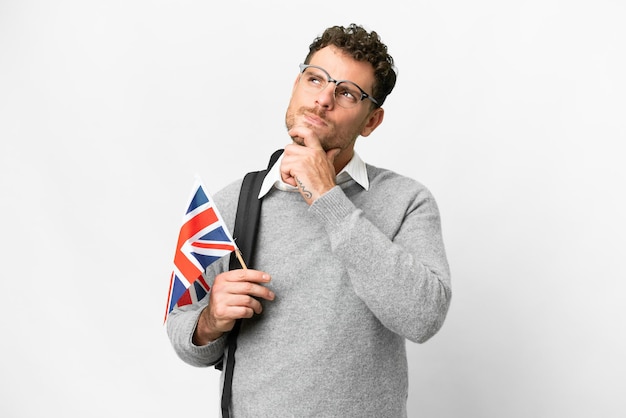 Photo brazilian man holding an united kingdom flag over isolated white background and looking up