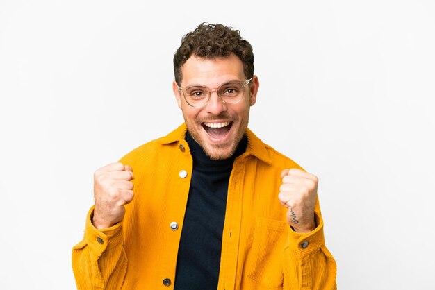 Uomo brasiliano su sfondo bianco isolato che celebra una vittoria nella posizione del vincitore