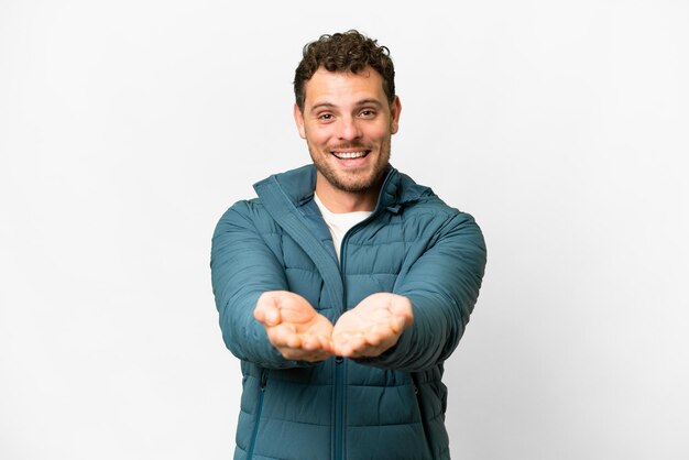 Brazilian man over isolated white background holding copyspace imaginary on the palm to insert an ad