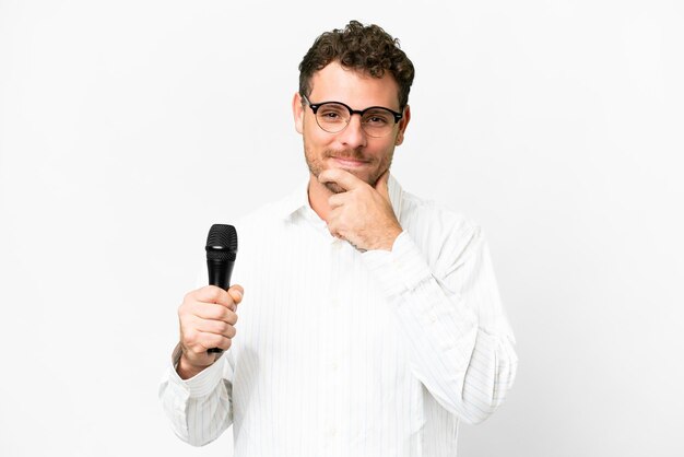 Brazilian man picking up a microphone over isolated white background thinking