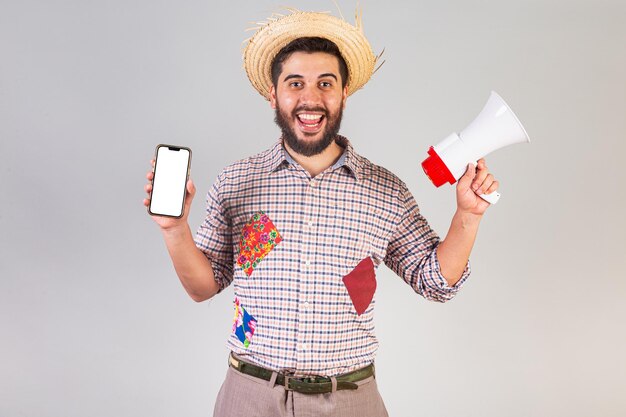 フェスタ ジュニーナの服を着たブラジル人男性がメガホンとスマートフォンでプロモーション広告を叫ぶアライアル聖ヨハネの祝日