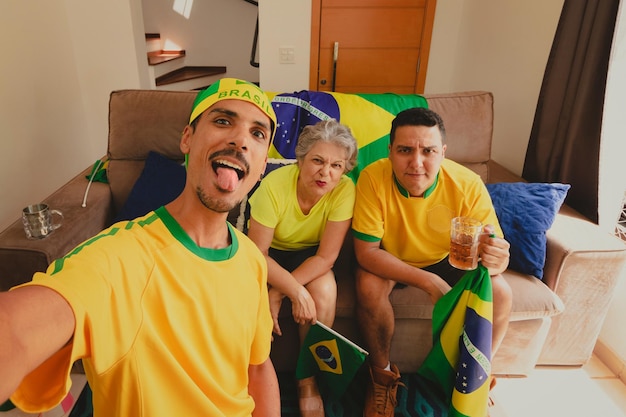 ブラジルの混血家族 サッカーの試合を見ながら居間でカップを祝う カップの試合を見ながら自撮り写真を撮る家族