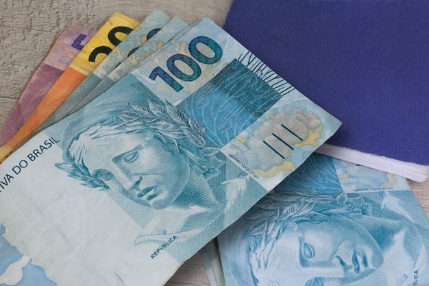 Brazilian money in paper and notebook on wooden surface