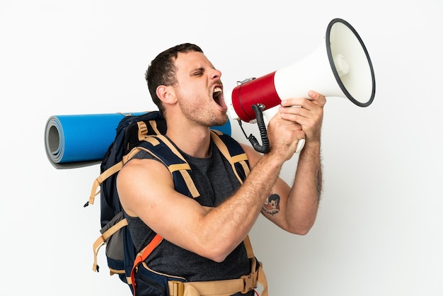 Brazilian mountaineer man with a big backpack over isolated white background shouting through a megaphone