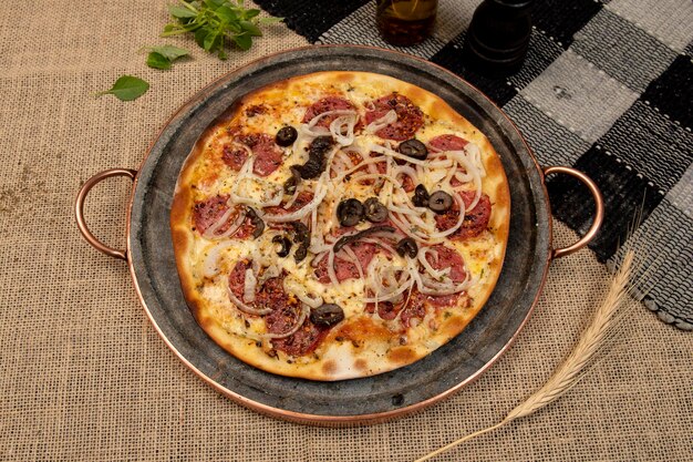 Foto pizza brasiliana con cipolla di formaggio pepperoni e oliva nera vista dall'alto