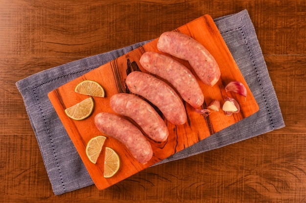 Brazilian pork leg sausage with garlic on wood cutting board isolated on wood