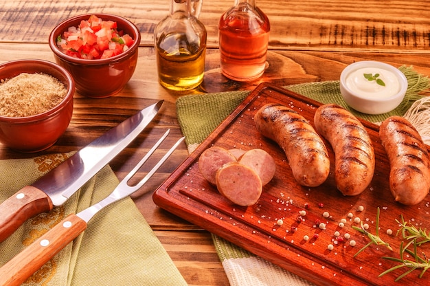 Колбаска из свинины по-бразильски с вилкой и ножом для барбекю
