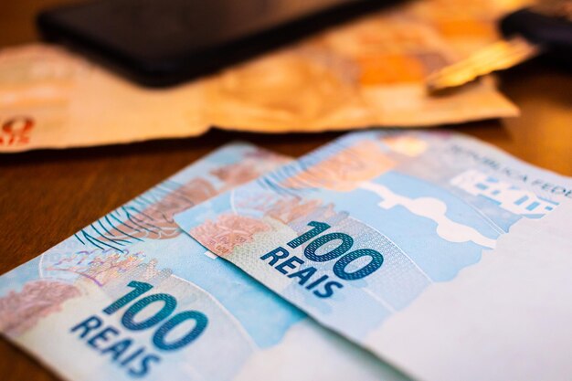 Brazilian Real banknotes in denominations of 100 Reais and 50 Reais on a table in closeup photo