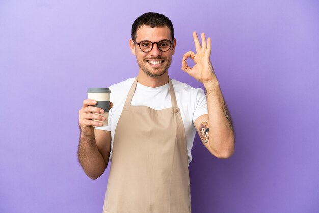 Cameriere brasiliano del ristorante sopra la parete viola isolata che mostra il segno giusto con le dita