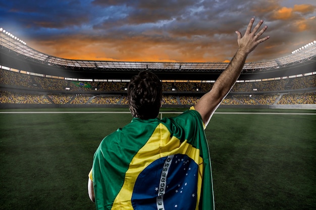 Brazilian soccer player with a Brazilian flag on his back, celebrating with the fans.