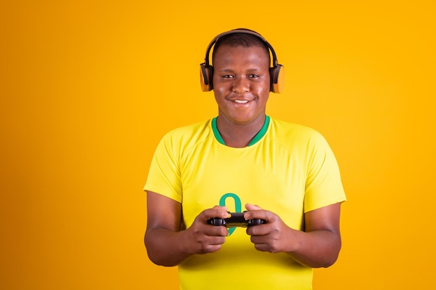 Brazilian soccer or soccer fan wearing yellow uniform and holding a video game controller on yellow background