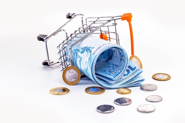 Brazilian supermarket cart and lots of money sprawled on the floor. Concept of crisis in the Brazilian economy