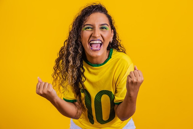 Brazilian supporter Brazilian woman fan celebrating on soccer or football match on yellow background Brazil colors