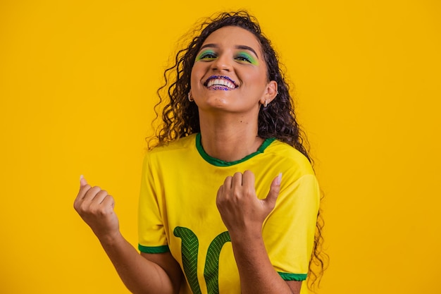 Brazilian supporter Brazilian woman fan celebrating on soccer or football match on yellow background Brazil colors
