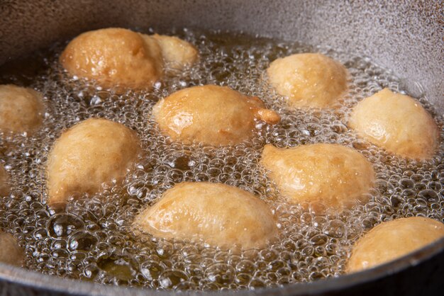 Brazilian sweet called bolinho de Chuva, being fried in a pan with oil, selective focus.