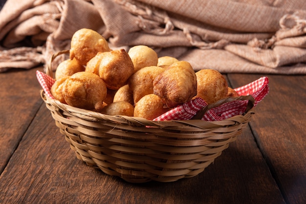 Brazilian sweet called bolinho de Chuva, placed in a basket on rustic wood, selective focus.