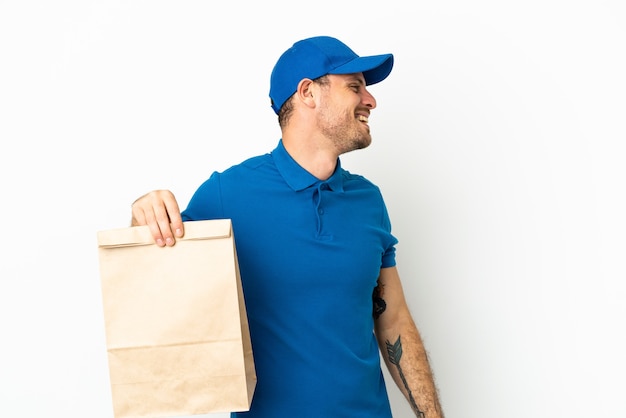 Brazilian taking a bag of takeaway food isolated on white background laughing in lateral position