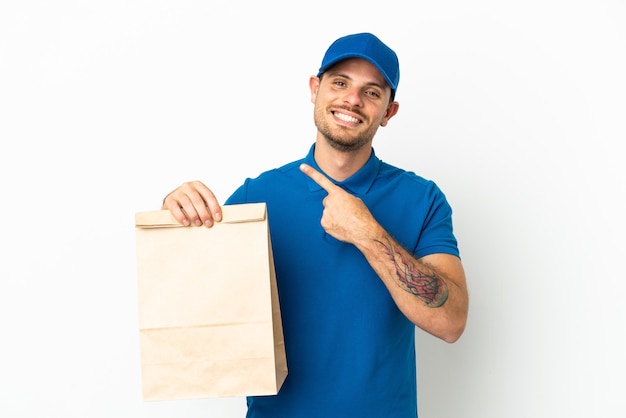 Brazilian taking a bag of takeaway food isolated on white background pointing to the side to present a product