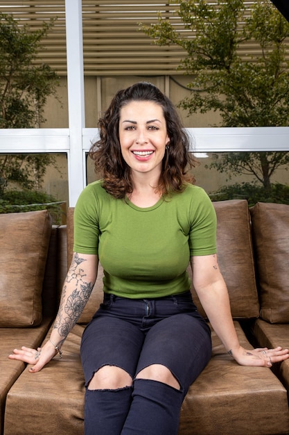 Brazilian tattooed and smiling sitting on the sofa