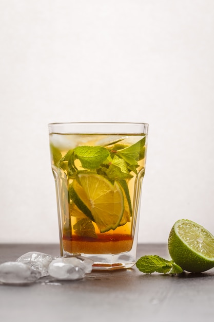 Brazilian traditional caipirinha with lime, sugar and mint. White background, dark table, copy space.