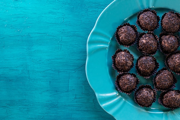 Brazilian traditional sweet brigadeiro on blue table.