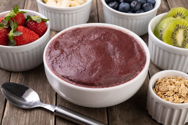 Brazilian typical acai bowl with fruits and muesli over wooden background.