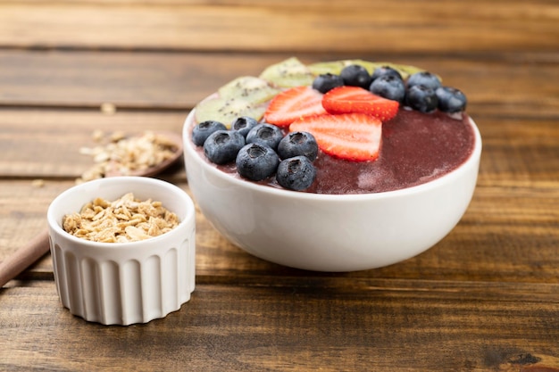 Brazilian typical acai bowl with kiwi blueberry granola and strawberry over wooden table