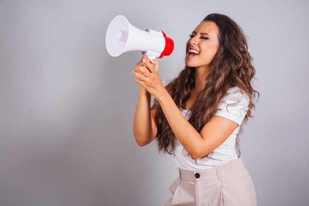 Brazilian woman brown hair holding megaphone announcing promotion discount Screaming and calling