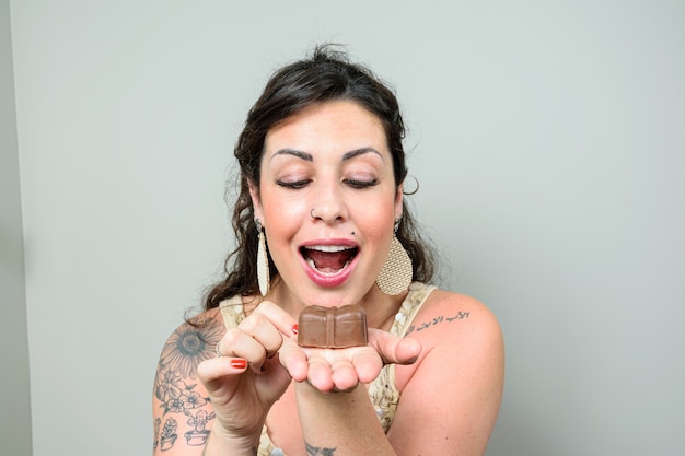 Brazilian woman, tattooed, with her mouth wide open ready to eat a Brazilian honey cake.