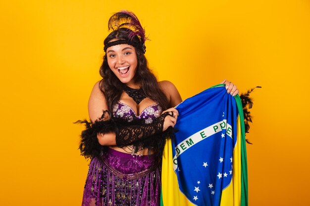 カーニバルの服を着たブラジル人女性が国旗を掲げている