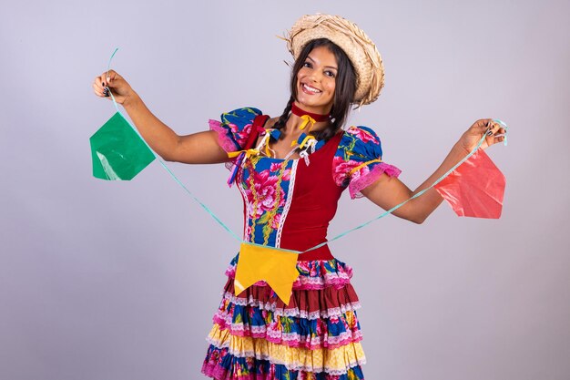 Photo brazilian woman with clothes from festa de sao joao festa junina holding flags