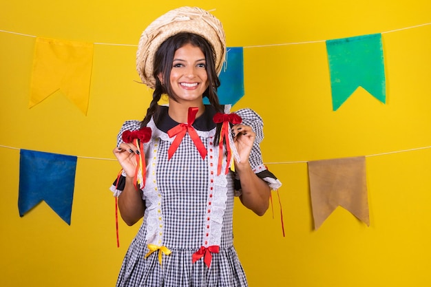 Foto donna brasiliana con abiti della festa de sao joao festa junina su sfondo giallo con bandiere