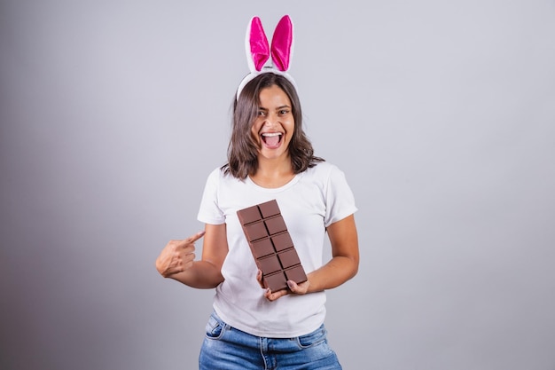 Brazilian woman with Easter bunny ears smiling happily holding Easter chocolate bar