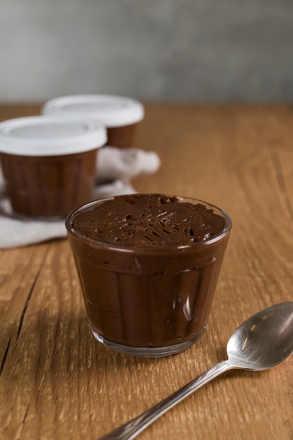 Foto dolce al cioccolato brasiliano chiamato brigadeiro in vaso su sfondo di legno della scrivania versione vegana