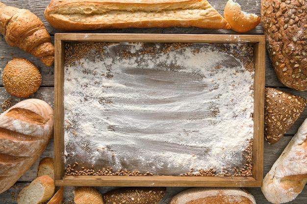 Bread bakery background, wooden tray top view with copy space, flour on wood