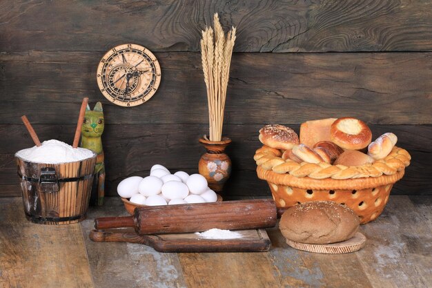 bread basket and raw eggs on old wooden background