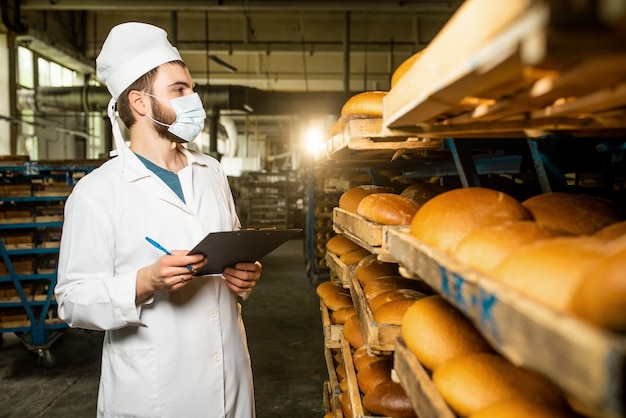 Foto pane. linea di produzione del pane. un uomo in uniforme. controllo sanitario.