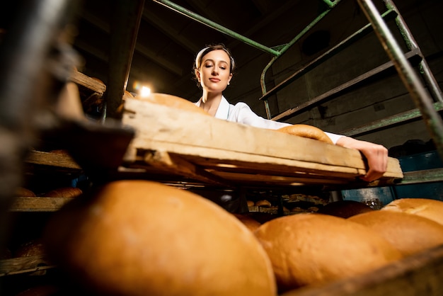 Foto pane. linea di produzione del pane. un uomo in uniforme. controllo sanitario.