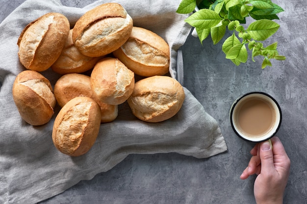 素朴な木のバスケット、春の葉、コーヒーカップを持つ手でパンのパン